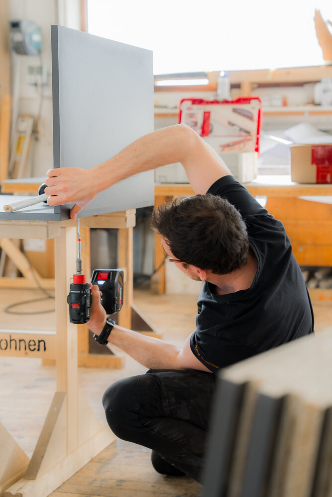 Ein Mann schraubt zwei Teile eines Möbelstücks zusammen 
