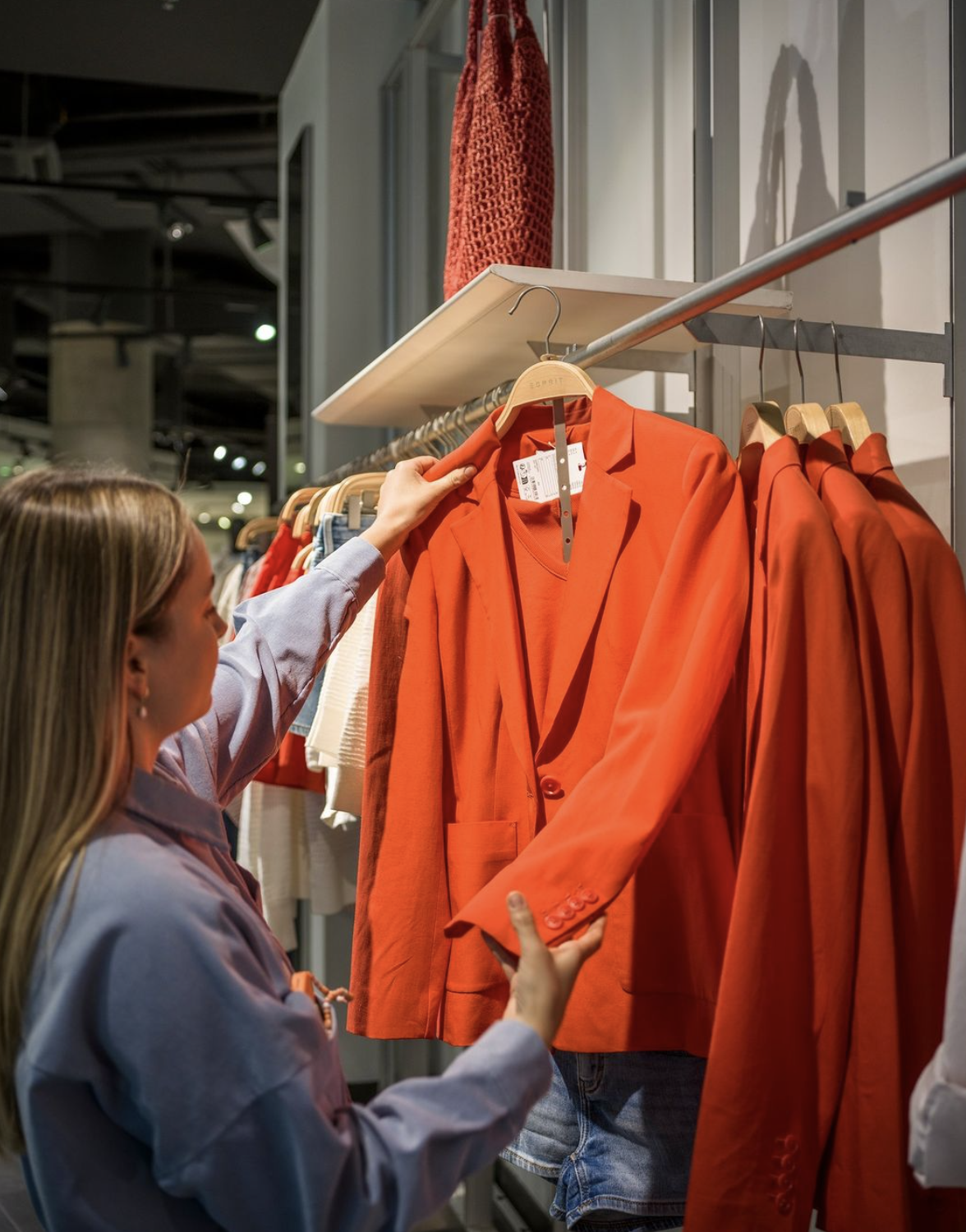 Eine Frau beim einkaufen, wie sie sich einen Blazer ansieht