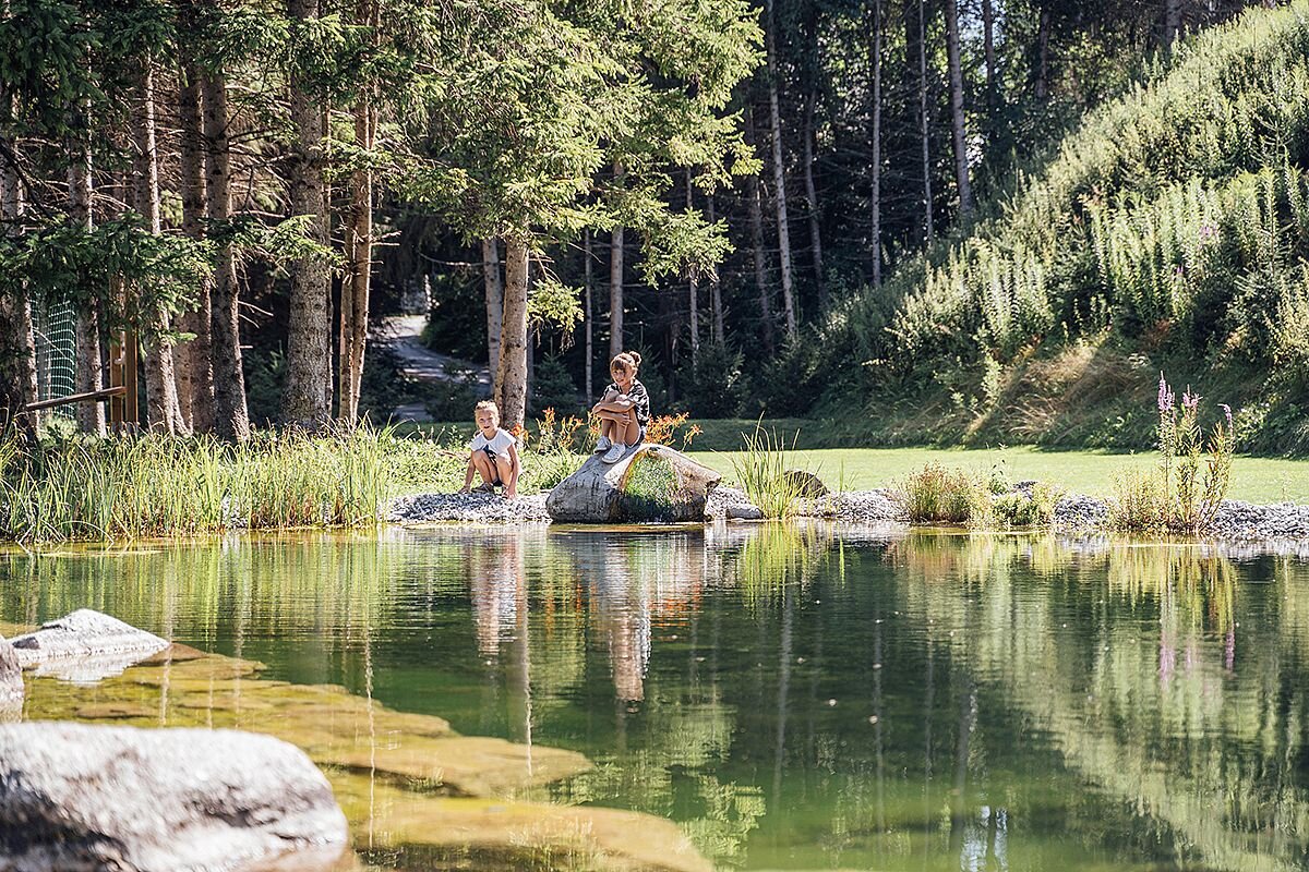 Der Teich im Garten mit zwei Kindern am Ufer